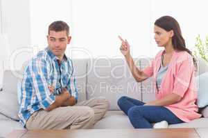 Woman pointing at man while sitting on sofa