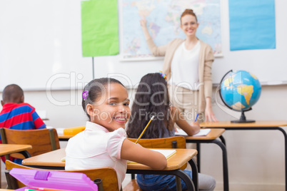 Cute pupils and teacher in classroom with globe