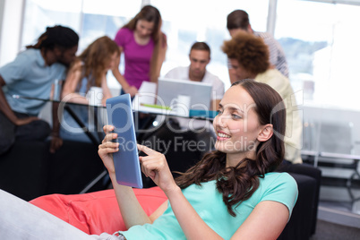 Student using digital tablet with friends in background