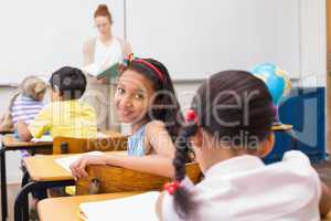 Cute pupil smiling at camera in classroom