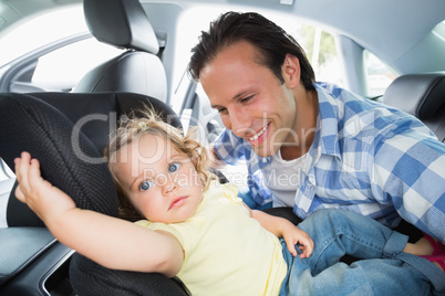 Father securing his baby in the car seat