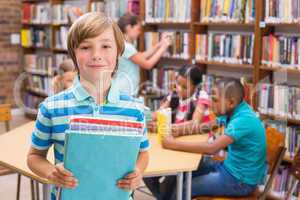 Cute pupil smiling at camera in library