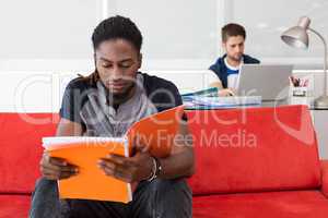 Casual young man reading folder in office