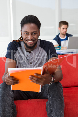 Smiling casual young man reading folder