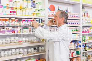 Focused pharmacist on the phone pointing medicine