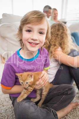 Happy boy holding kitten while sitting with family