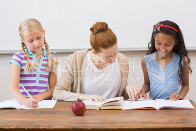 Teacher and pupils working at desk together