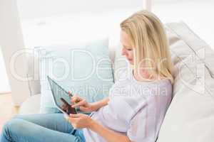 Woman using digital tablet while sitting on sofa