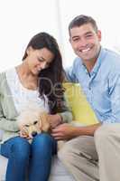 Couple playing with puppy on sofa