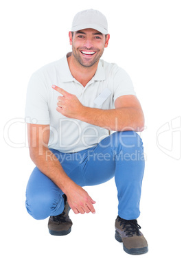 Handyman crouching while pointing on white background