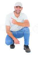 Handyman crouching while pointing on white background