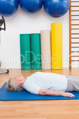 Senior woman lying on exercise mat