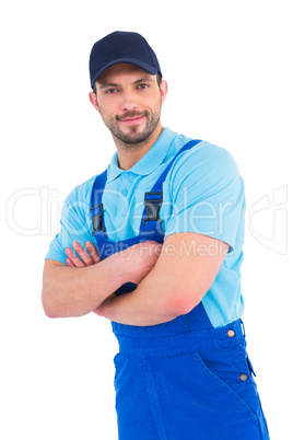 Smiling male handyman in coveralls standing arms crossed