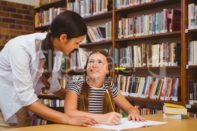 Teacher assisting girl with homework in library