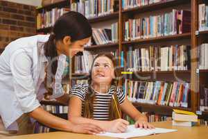 Teacher assisting girl with homework in library