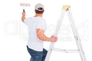 Handyman climbing ladder while using paint roller