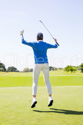 Female golfer leaping and cheering
