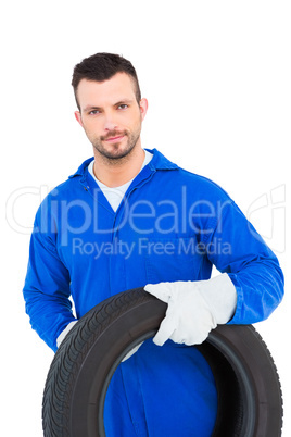 Smiling male mechanic holding tire