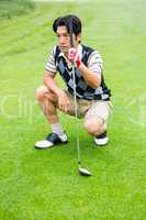 Crouching golfer holding club looking away