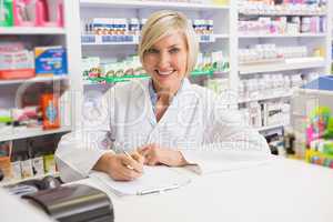 Smiling pharmacist writing on clipboard