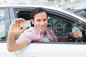 Man smiling and holding his driving license