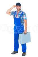 Happy manual worker wearing cap while carrying toolbox