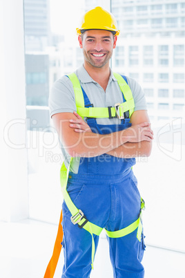 Manual worker wearing safety harness in bright office