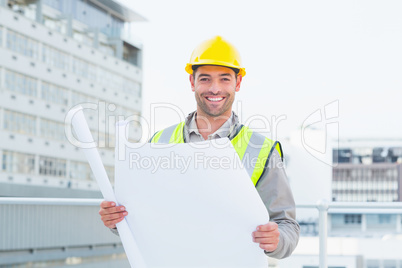 Happy architect holding blueprints outside building