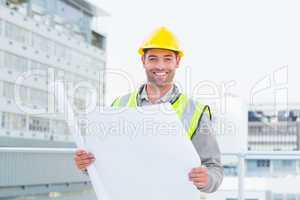 Happy architect holding blueprints outside building
