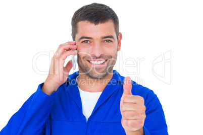 Mechanic using mobile phone while gesturing thumbs up