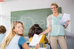 Teacher handing paper to student in class