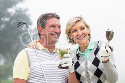 Happy golfing couple with trophy