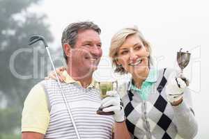 Happy golfing couple with trophy