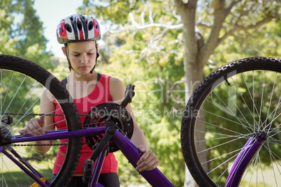 Fit woman fixing the chain on her bike