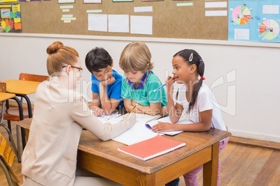 Teacher and pupils working at desk together