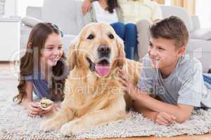 Siblings lying with dog while parents sitting on sofa