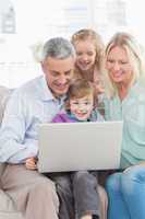 Family of four using laptop