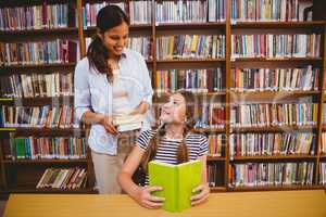 Teacher and girl reading book in library