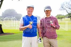 Golfing friends holding cups smiling at camera