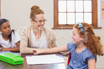 Pretty teacher helping pupil in classroom