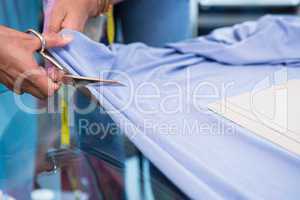 Hands cutting fabric at table