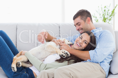 Couple with puppy relaxing on sofa