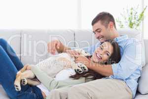 Couple with puppy relaxing on sofa