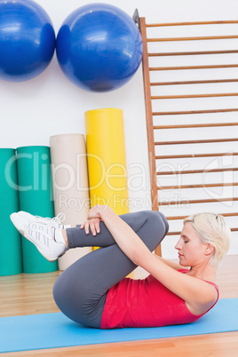 Blonde woman working on exercise mat