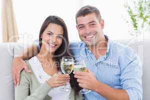 Loving couple toasting wine glasses at home