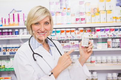 Smiling doctor pointing a drug bottle