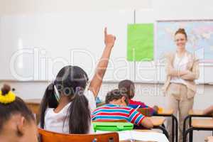 Pupils raising hand during geography lesson in classroom