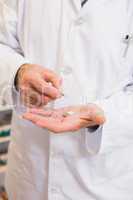 Mid section of pharmacist holding pills