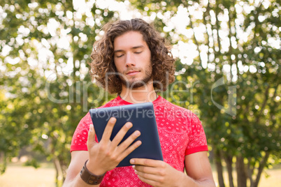 Handsome hipster using tablet pc in the park