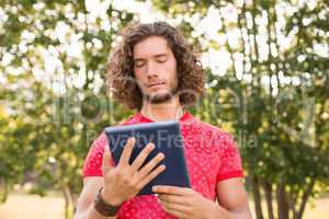 Handsome hipster using tablet pc in the park